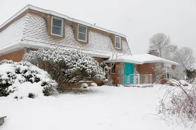 a house with a blue door covered in snow at Daydream Mountain Art Chateau in Catskill