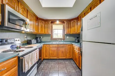 a kitchen with wooden cabinets and a white refrigerator at Buskirk Vacation Rental with Deck and Putting Green! in Buskirk