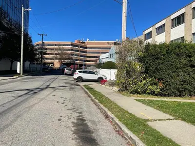 an empty street with a white car parked in front of a building at Modern Home off I-95 Perfect for Families & Business Stay with Ample Parking in Stamford