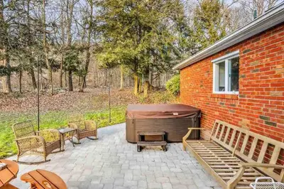 a backyard with a hot tub and chairs and a brick building at 3 Bedroom Hilltop Escape with 5 Private Acres and Hot Tub in Marlboro
