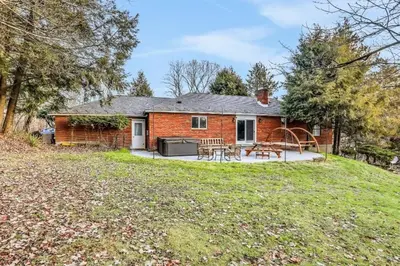 a brick house with a patio and a yard at 3 Bedroom Hilltop Escape with 5 Private Acres and Hot Tub in Marlboro