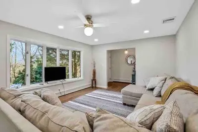 a living room with a large couch and a flat screen tv at 3 Bedroom Hilltop Escape with 5 Private Acres and Hot Tub in Marlboro