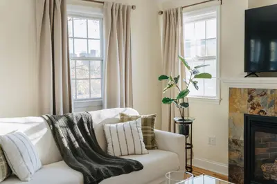 a living room with a white couch and a fireplace at Urban Downtown Stamford Home 45 min to NYC with Garage And Yard in Stamford