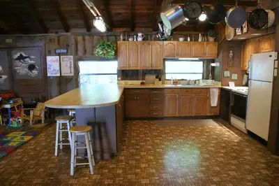 a kitchen with wooden cabinets and a kitchen island with stools at Cabin A-frame - Beautiful Cabin in Laurel Island in East Hampton
