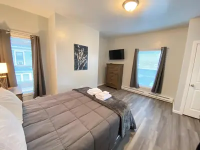 a bedroom with a large bed and two windows at Double Play Apt 2 All Star Baseball Rentals in Oneonta