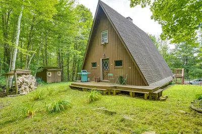a cabin in the woods with a gambrel roof at A-Frame Cabin with Furnished Deck in Becket! in Becket
