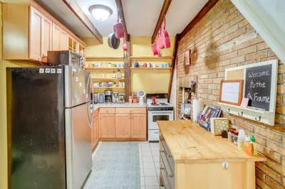 a kitchen with a refrigerator and a table in it at A-Frame Cabin with Furnished Deck in Becket! in Becket