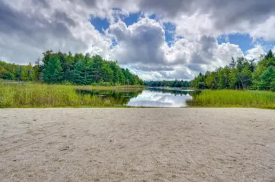 a body of water with trees and clouds at A-Frame Cabin with Furnished Deck in Becket! in Becket