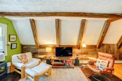a living room with a couch and a tv at A-Frame Cabin with Furnished Deck in Becket! in Becket