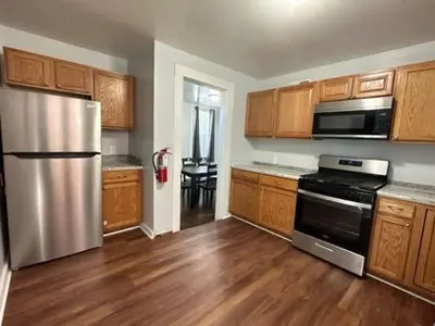 a kitchen with a stainless steel refrigerator and wooden cabinets at Home Plate Apt 1 All Star Baseball Rentals in Oneonta