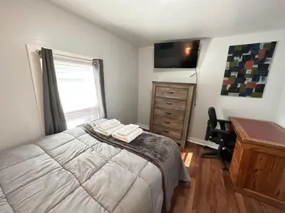a bedroom with a bed and a desk and a television at Home Plate Apt 2 All Star Baseball Rentals in Oneonta