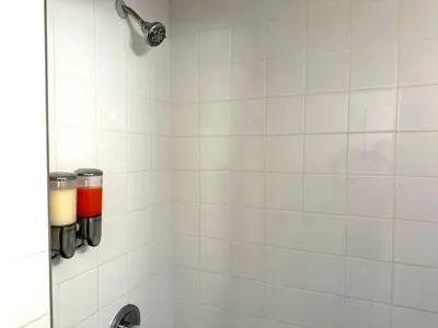 a shower with a white tiled wall and a sink at 4-A Diamond in Yonkers in Yonkers