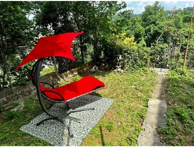 a red chair with an umbrella sitting in the grass at 4-A Diamond in Yonkers in Yonkers
