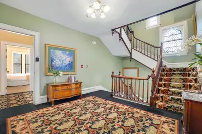 a living room with a staircase and a rug at DeBary Inn in Summit