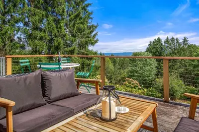 a patio with a couch and a table on a deck at Relaxing Catskill Escape- Mountain Views - Hot Tub - Fire Pit - Heated Pool in Catskill