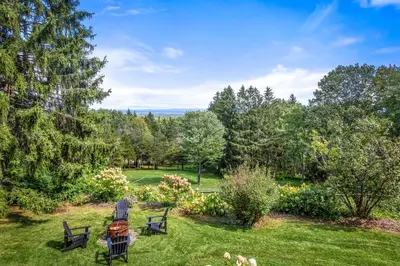 a garden with chairs and a table in the grass at Relaxing Catskill Escape- Mountain Views - Hot Tub - Fire Pit - Heated Pool in Catskill