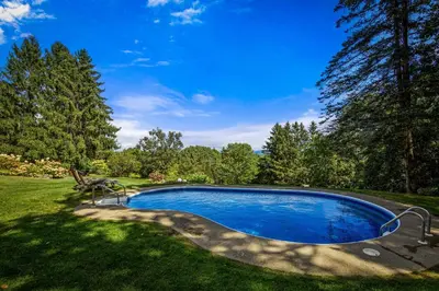 a swimming pool in a yard with trees at Relaxing Catskill Escape- Mountain Views - Hot Tub - Fire Pit - Heated Pool in Catskill