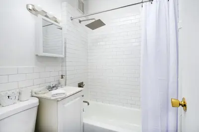 a white bathroom with a sink and a shower at 74-1C New Studio With private outdoors - GYM in New York
