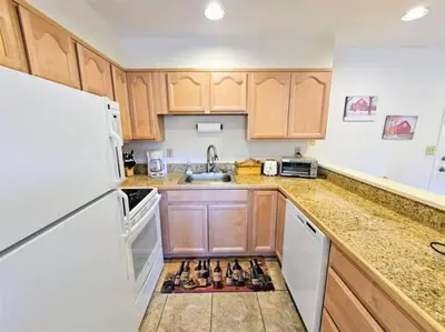 a kitchen with wooden cabinets and a white refrigerator at Mt Snow Condo with Pool Mountain Views Half Mile to Mtn in Dover