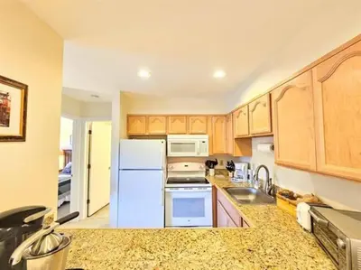 a kitchen with wooden cabinets and a white refrigerator at Mt Snow Condo with Pool Mountain Views Half Mile to Mtn in Dover
