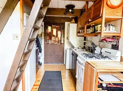a kitchen with a staircase leading to a kitchen with a stove at Sunday Hollow in Margaretville