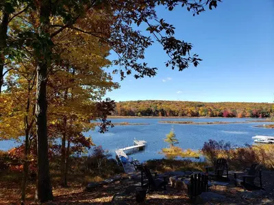 a boat is docked on a lake with trees at Magical Waterfront with 4-Season fun in Ski Resort in Lackawaxen