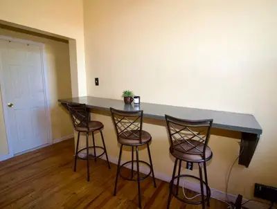 a bar in a room with three bar stools at Tuk Ahoy - Sunset Suite (3B) with Shared Spaces in Brooklyn