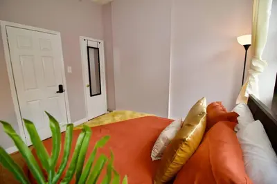 a bedroom with a bed with gold pillows and a plant at Tuk Ahoy - Sunset Suite (3B) with Shared Spaces in Brooklyn