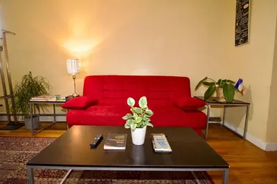 a living room with a red couch and a coffee table at Tuk Ahoy - Sunset Suite (3B) with Shared Spaces in Brooklyn