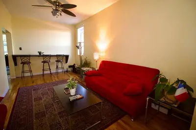 a living room with a red couch and a table at Tuk Ahoy - Sunset Suite (3B) with Shared Spaces in Brooklyn