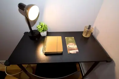 a black desk with a book and a lamp and a notebook at Tuk Ahoy - Sunset Suite (3B) with Shared Spaces in Brooklyn