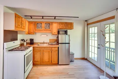 a kitchen with white appliances and wooden cabinets at Charming Claverack Retreat with Serene Deck! in Claverack
