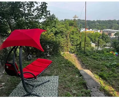 a red chair with a red umbrella in the grass at 5-A Diamond in Yonkers in Yonkers