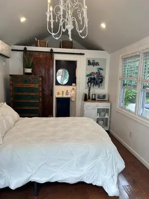 a bedroom with a white bed and a chandelier at Adorable 1 bedroom cottage in Forest Hills