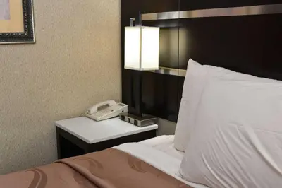 a hotel room with a phone next to a bed at Quality Inn East Stroudsburg - Poconos in East Stroudsburg