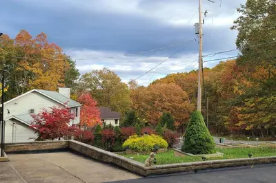 a house with a yard with trees in autumn at Luxury getaway in woods, Jacuzzi, Hot Tub, Pool in Bushkill