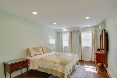 a bedroom with a bed and a dresser and two windows at Fire Pit and On-Site Pond Hudson Valley Home! in Wappingers Falls
