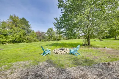 two blue chairs sitting next to a fire pit in a field at Fire Pit and On-Site Pond Hudson Valley Home! in Wappingers Falls