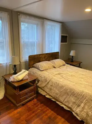 a bedroom with a large bed and two windows at Comfortable home away from home in East Hartford