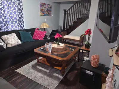 a living room with a black couch and a table at Comfortable home away from home in East Hartford