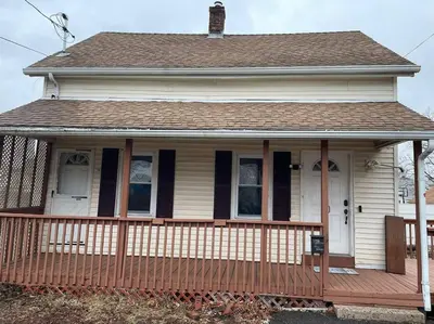 a white house with a porch and a brown roof at Comfortable home away from home in East Hartford