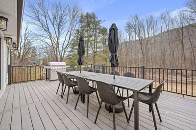 a wooden deck with a table and chairs and umbrellas at Chateau Bungalow - Ski Belleayre, Hunter in Shandaken