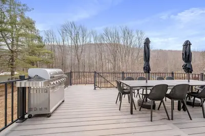 a deck with a grill and a table and chairs at Chateau Bungalow - Ski Belleayre, Hunter in Shandaken