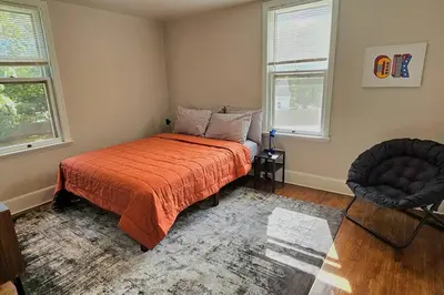 a bedroom with a bed and a chair and two windows at Modern 4BDRM West Hartford Home In Great Location! in West Hartford
