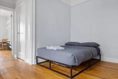 a bed in a room with a white wall at Live Upper Manhattan on a Budget in New York