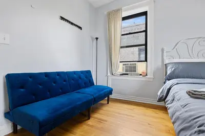a blue couch in a bedroom with a window at Live Upper Manhattan on a Budget in New York