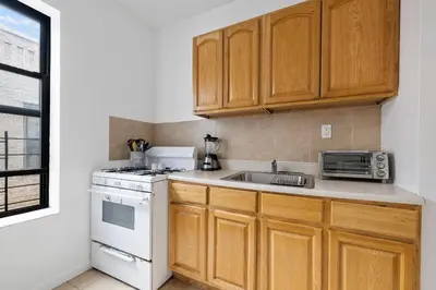 a kitchen with wooden cabinets and a sink and a stove at Live Upper Manhattan on a Budget in New York