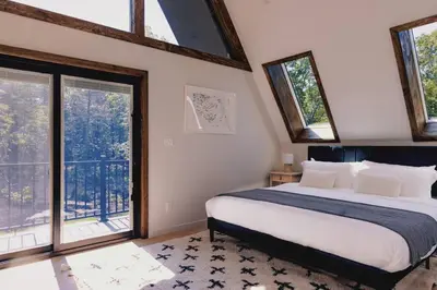 a bedroom with a large bed and windows at Emberwood Lodge - Luxury Cabin, Kid Friendly in Catskill