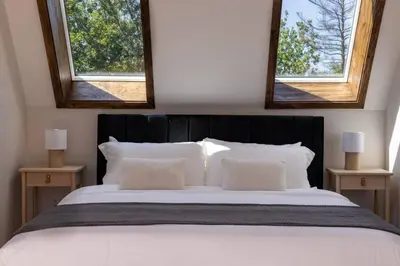 a bedroom with a large bed with two windows at Emberwood Lodge - Luxury Cabin, Kid Friendly in Catskill