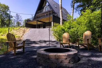 two chairs and a fire pit in front of a house at Emberwood Lodge - Luxury Cabin, Kid Friendly in Catskill